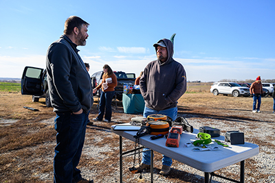 Two persons talking at a display table during a field day.